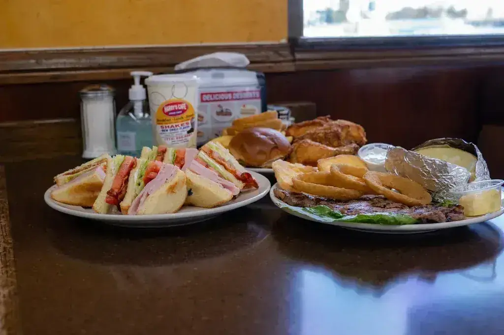 A club sandwich plate and a steak plate with onion rings and a baked potato at Harry's Cafe, a lunch restaurant on Katella Ave, Stanton, CA