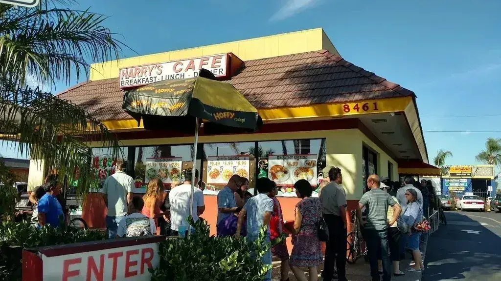 The Harry's Cafe storefront and sign with a line of customers waiting outside on Katella Ave, Stanton, CA