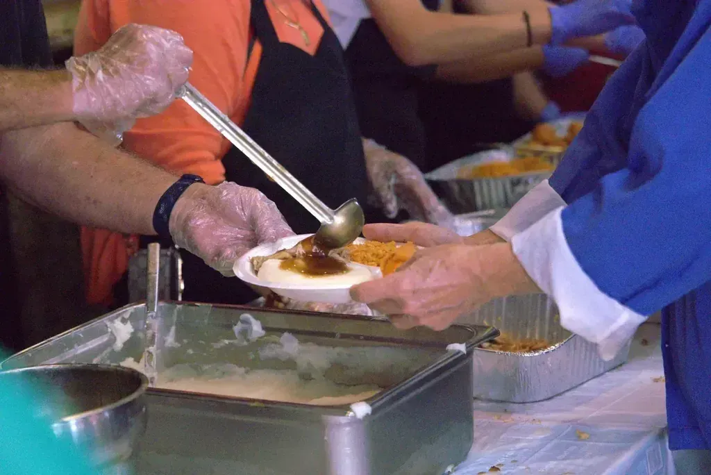 Volunteers ladling mashed potatoes and gravy at the Thanksgiving serving line at Harry's Cafe, Katella Ave, Stanton, CA