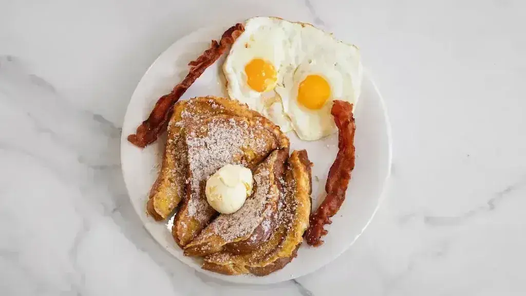 French toast with butter and powdered sugar beside bacon and two eggs at Harry's Cafe, Katella Ave, Stanton, CA