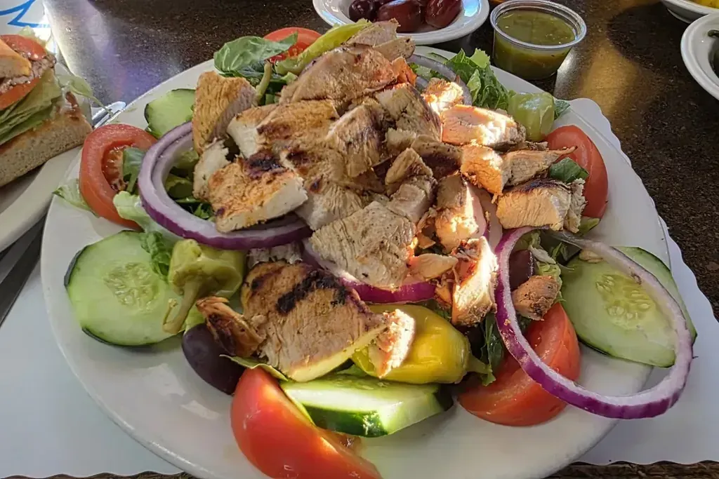 A Greek chicken salad with tomato, cucumber, and red onion from the Greek menu at Harry's Cafe, Katella Ave, Stanton, CA