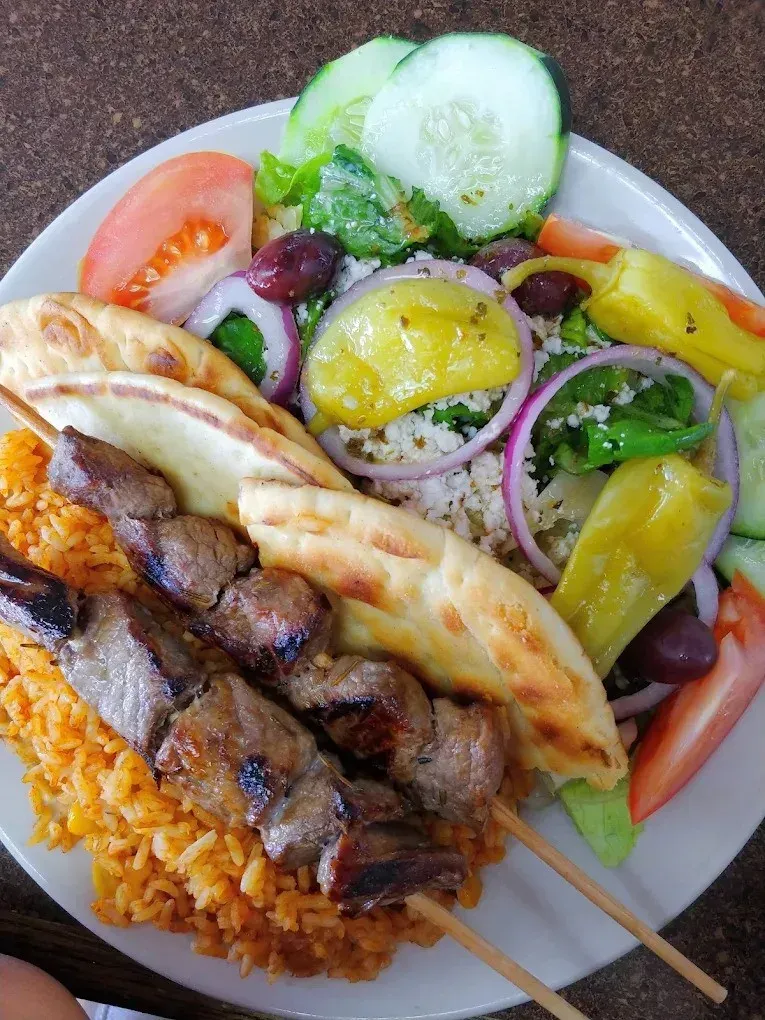 A beef kebob plate with rice and pita beside a Greek salad, on the kebob menu at Harry's Cafe, Katella Ave, Stanton, CA