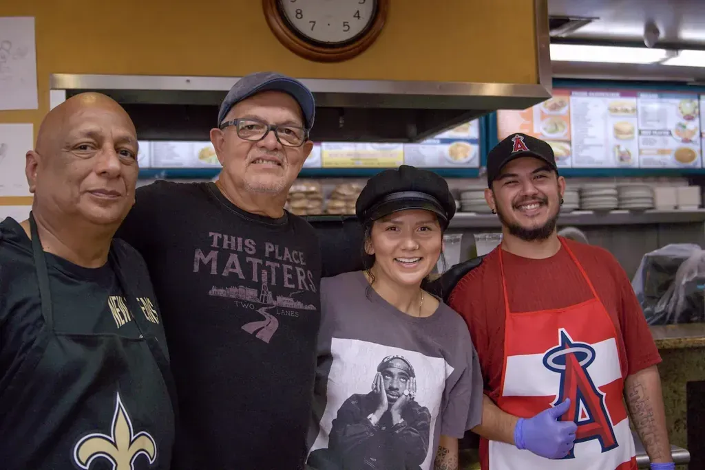 Four staff members at the Harry's Cafe restaurant on Katella Ave, Stanton, CA, posing together by the kitchen pass