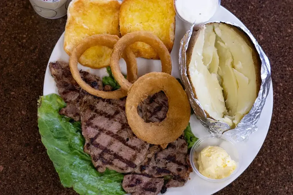 A grilled steak dinner with a baked potato and onion rings at Harry’s Cafe, Katella Ave, Stanton, CA.